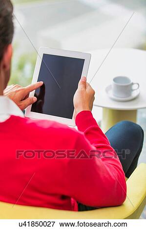 Portrait of attractive businessman using digital tablet while sitting and drinking coffee in lobby View Large Photo Image Stock Photo - Portrait of attractive businessman using digital tablet while sitting and drinking coffee in lobby. Fotosearch