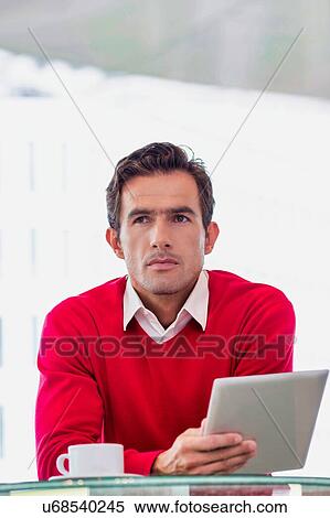 Portrait of attractive businessman using digital tablet while sitting and drinking coffee in lobby View Large Photo Image Stock Photography - Portrait of attractive businessman using digital tablet while sitting and drinking coffee in lobby. Fotosearch