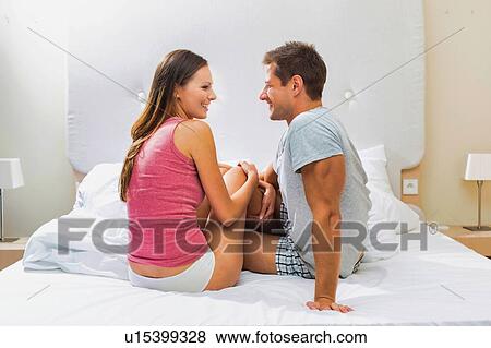 Stock Photo - Portrait of attractive couple sitting in bed at home. Fotosearch
