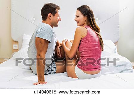 Stock Photography - Portrait of attractive couple sitting in bed at home. Fotosearch