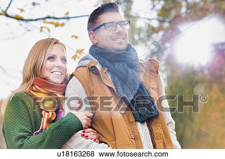 Stock Photo - Portrait of attractive man and woman standing in park. Fotosearch