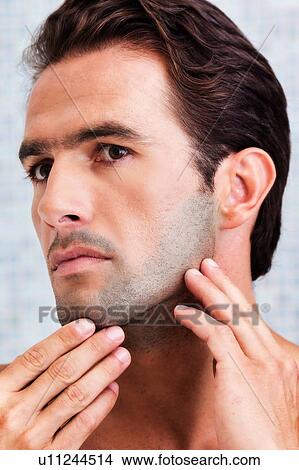 Picture - Portrait of attractive man checking his face in the mirror. Fotosearch