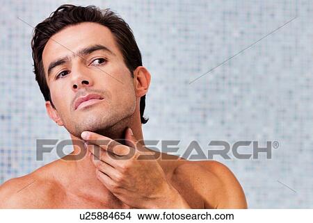 Picture - Portrait of attractive man checking his face in the mirror. Fotosearch