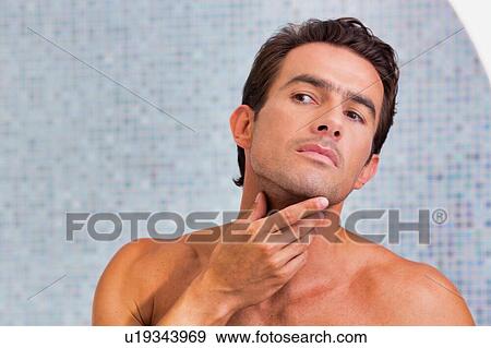 Stock Photo - Portrait of attractive man checking his face in the mirror. Fotosearch