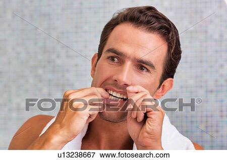 Portrait of attractive man looking in the mirror while flossing hsi teeth View Large Photo Image Stock Photo - Portrait of attractive man looking in the mirror while flossing hsi teeth . Fotosearch