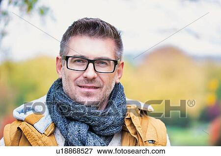 Stock Photo - Portrait of attractive man standing in park. Fotosearch
