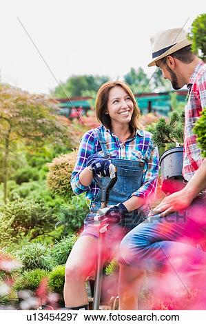 Portrait of beautiful gardener smiling and holding shovel while talking to man in the garden View Large Photo Image Stock Photo - Portrait of beautiful gardener smiling and holding shovel while talking to man in the garden. Fotosearch