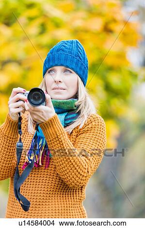 Portrait of beautiful woman photographing lovely maple trees in park View Large Photo Image Picture - Portrait of beautiful woman photographing lovely maple trees in park. Fotosearch