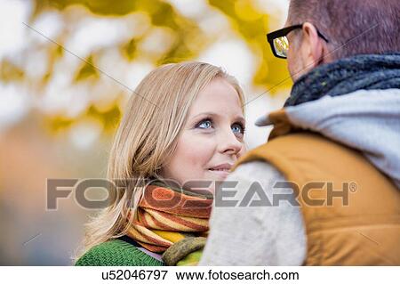 Stock Photo - Portrait of beautiful woman showing affection while talking to her husband in park. Fotosearch