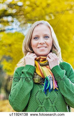 Stock Photo - Portrait of Beautiful woman standing and smiling while holding her scarf. Fotosearch