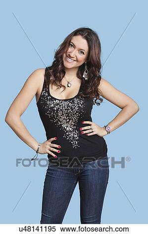 Portrait of beautiful woman with hands on hips smiling over blue background View Large Photo Image Stock Photography - Portrait of beautiful woman with hands on hips smiling over blue background. Fotosearch