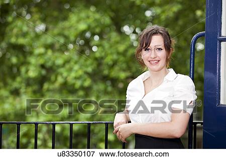 Stock Photo - Portrait of beautiful young businesswoman standing by railing. Fotosearch