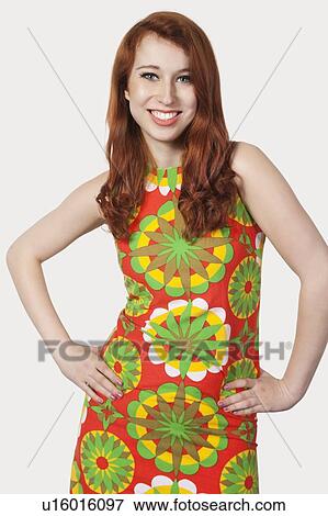 Portrait of beautiful young woman in multicolored dress posing against gray background View Large Photo Image Stock Photo - Portrait of beautiful young woman in multicolored dress posing against gray background. Fotosearch