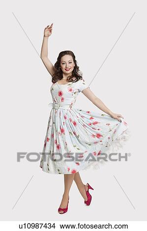 Picture - Portrait of beautiful young woman wearing dress standing in dance pose against white background. Fotosearch