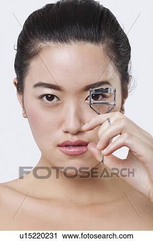 Portrait of beautiful young woman using eyelash curler against white background View Large Photo Image Stock Image - Portrait of beautiful young woman using eyelash curler against white background. Fotosearch