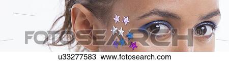 Stock Image - Portrait of beautiful young woman with stars on her face against white background. Fotosearch