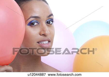 Portrait of beautiful young woman with balloons against white background View Large Photo Image Stock Photo - Portrait of beautiful young woman with balloons against white background. Fotosearch