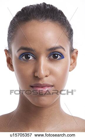 Stock Photo - Portrait of beautiful young woman with blue eyeshadow against white background. Fotosearch