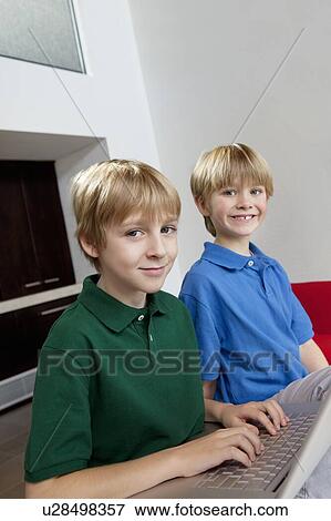 Stock Photo - Portrait of blond brothers using laptop. Fotosearch