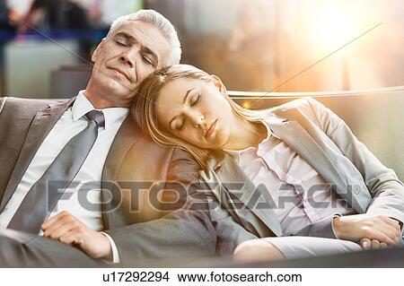 Portrait of business couple sleeping while waiting for boarding in airport with lens flare View Large Photo Image Picture - Portrait of business couple sleeping while waiting for boarding in airport with lens flare. Fotosearch
