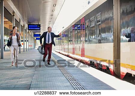 Stock Photo - Portrait of business people running to catch the train in station. Fotosearch
