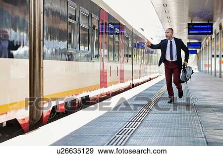 Stock Photo - Portrait of business people running to catch the train in station. Fotosearch