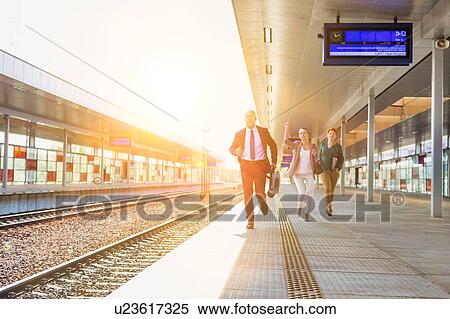 Stock Photography - Portrait of business people running to catch the train in station. Fotosearch