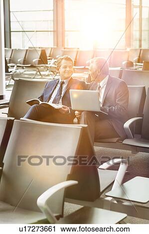 Portrait of business people sitting while waiting for boarding in airport View Large Photo Image Stock Image - Portrait of business people sitting while waiting for boarding in airport. Fotosearch