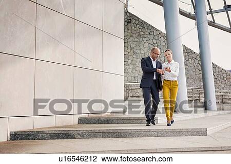 Stock Image - Portrait of businessman and businesswoman discussing plans before meeting . Fotosearch