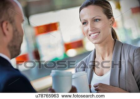 Portrait of businessman and businesswoman holding cup of coffee while talking and waiting for the train View Large Photo Image Stock Image - Portrait of businessman and businesswoman holding cup of coffee while talking and waiting for the train. Fotosearch