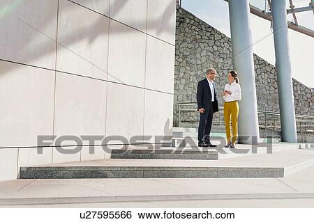 Stock Photograph - Portrait of businessman and businesswoman discussing plans before meeting . Fotosearch