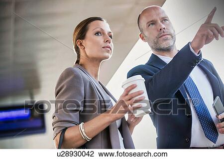 Portrait of businessman gesturing while talking to young attractive businesswoman in train station View Large Photo Image Stock Image - Portrait of businessman gesturing while talking to young attractive businesswoman in train station. Fotosearch
