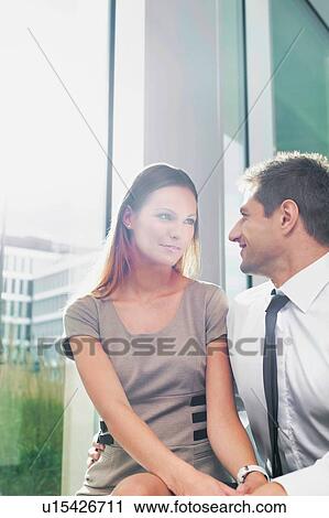 Stock Image - Portrait of businessman giving partner love and affection in hotel lobby. Fotosearch