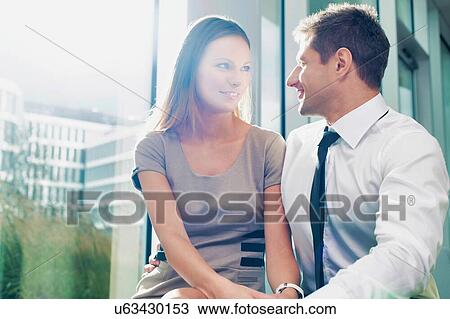 Stock Image - Portrait of businessman giving partner love and affection in hotel lobby. Fotosearch