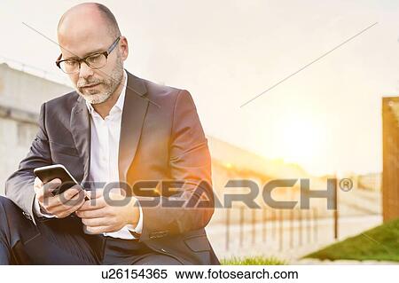 Portrait of businessman using digital tablet while sitting outside the office View Large Photo Image Stock Photography - Portrait of businessman using digital tablet while sitting outside the office. Fotosearch