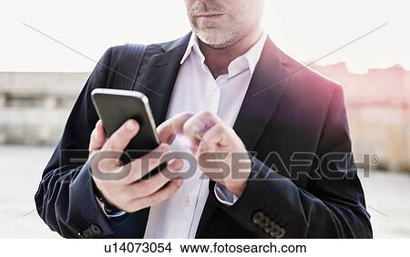 Portrait of businessman using smartphone while leaning on wall View Large Photo Image Picture - Portrait of businessman using smartphone while leaning on wall. Fotosearch