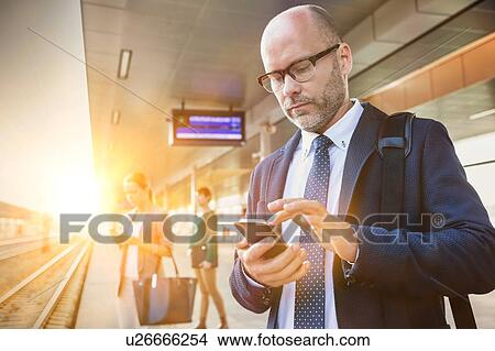 Portrait of businessman using smartphone while waiting for the train in station View Large Photo Image Picture - Portrait of businessman using smartphone while waiting for the train in station. Fotosearch