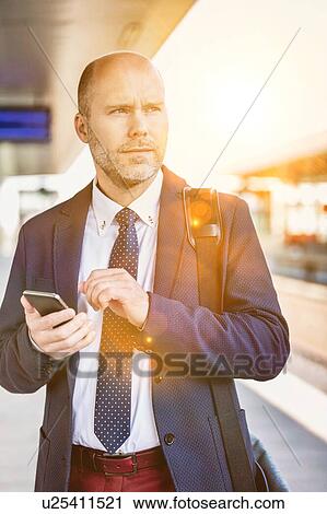 Portrait of businessman using smartphone while waiting for the train in station View Large Photo Image Stock Image - Portrait of businessman using smartphone while waiting for the train in station. Fotosearch