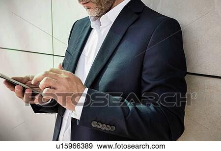Portrait of businessman using smartphone while leaning on wall View Large Photo Image Stock Photo - Portrait of businessman using smartphone while leaning on wall. Fotosearch