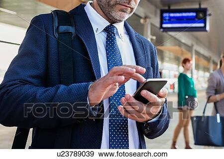 Portrait of businessman using smartphone while waiting for the train in station View Large Photo Image Stock Photo - Portrait of businessman using smartphone while waiting for the train in station. Fotosearch