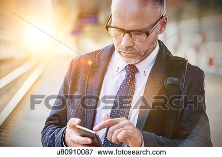 Portrait of businessman using smartphone while waiting for the train in station View Large Photo Image Stock Photo - Portrait of businessman using smartphone while waiting for the train in station. Fotosearch