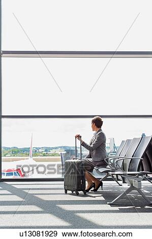 Stock Photo - Portrait of businesswoman sititng while waiting for boarding in airport . Fotosearch