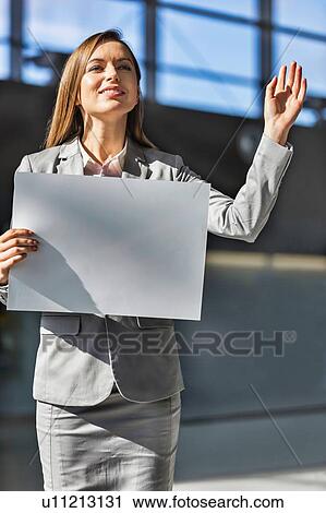 Portrait of businesswoman standing while holding blank white board in arrival area at airport View Large Photo Image Stock Image - Portrait of businesswoman standing while holding blank white board in arrival area at airport. Fotosearch
