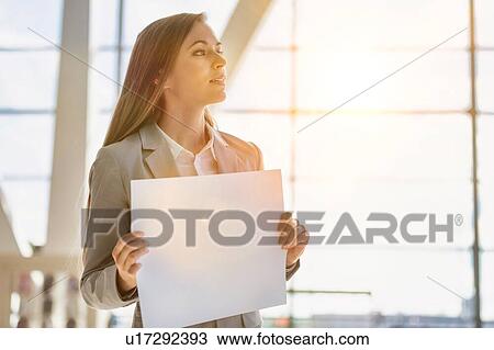 Portrait of businesswoman standing while holding blank white board in arrival area at airport View Large Photo Image Stock Image - Portrait of businesswoman standing while holding blank white board in arrival area at airport. Fotosearch