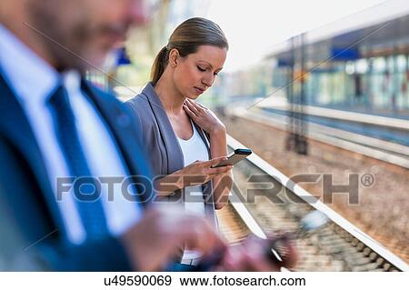 Portrait of businesswoman using smartphone while waiting for the train in station View Large Photo Image Stock Photo - Portrait of businesswoman using smartphone while waiting for the train in station. Fotosearch