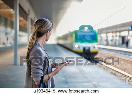 Portrait of businesswoman using smartphone while waiting for the train in station View Large Photo Image Stock Photography - Portrait of businesswoman using smartphone while waiting for the train in station. Fotosearch