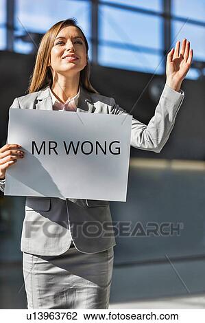 Portrait of businesswoman waving for her boss while holding blank white board in arrival area at airport View Large Photo Image Stock Image - Portrait of businesswoman waving for her boss while holding blank white board in arrival area at airport. Fotosearch