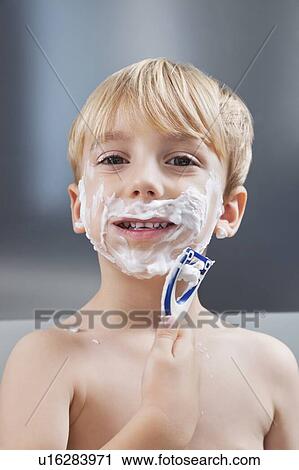 Stock Image - Portrait of Caucasian boy pretending to shave his face. Fotosearch