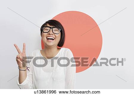 Portrait of cheerful young woman gesturing peace sign against Japanese flag View Large Photo Image Stock Photograph - Portrait of cheerful young woman gesturing peace sign against Japanese flag. Fotosearch