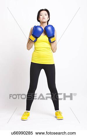 Portrait of confident Asian woman wearing boxing gloves against white background View Large Photo Image Stock Photography - Portrait of confident Asian woman wearing boxing gloves against white background. Fotosearch
